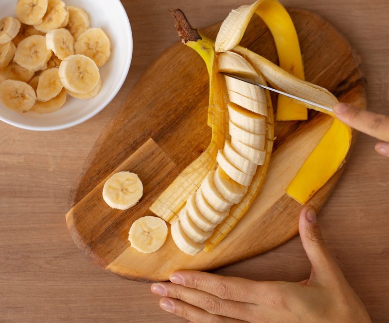 Person slicing a ripe banana