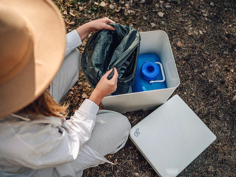 Woman emptying Trelino portable composting toilet.