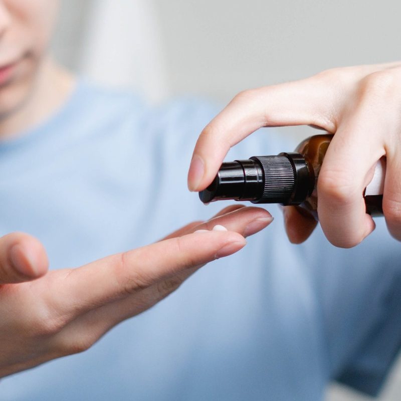 Man applying face serum to hand in bathroom