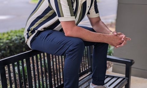 Man on a bench wearing a hat and polo