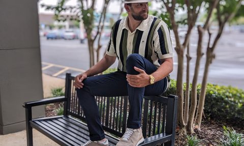 Man on a bench wearing a hat and polo