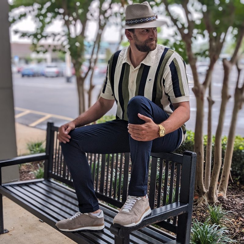 Man on a bench wearing a hat and polo