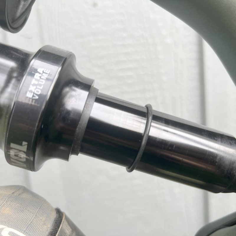 A close-up of the rear shock of a mountain bike showing the rubbing ring that helps the rider find the sag percentage
