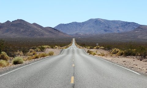 Isolated stretch of highway in Death Valley with mountains in the background