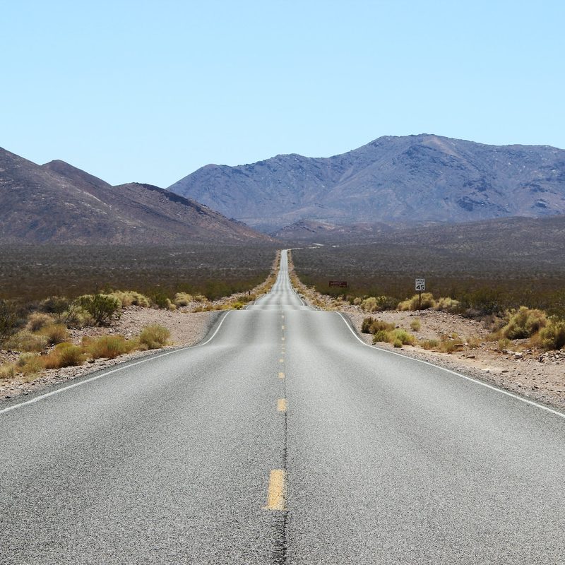 Isolated stretch of highway in Death Valley with mountains in the background