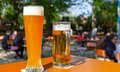 A wheat beer and a pils are standing on a table in a beer garden