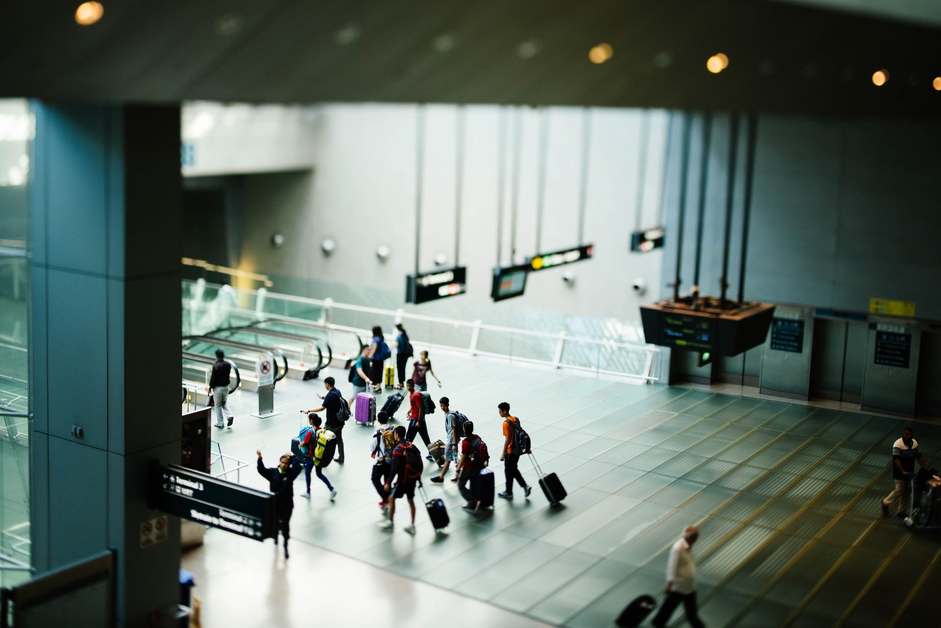 Travelers pass through an uncrowded airport terminal lobby