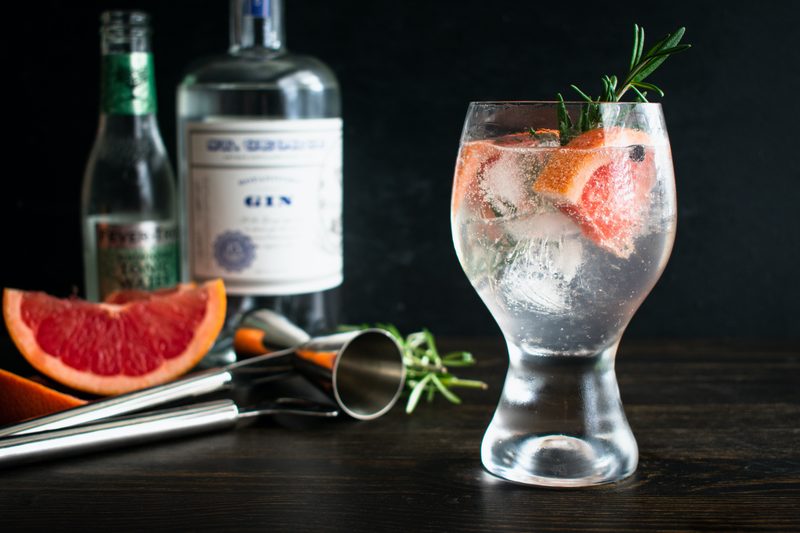 Elderflower Spanish Gin & Tonic: A gin and tonic cocktail garnished with pink grapefruit, juniper berries, and a rosemary sprig