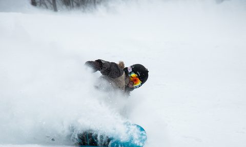 A snowboarder sprays snow into the air.