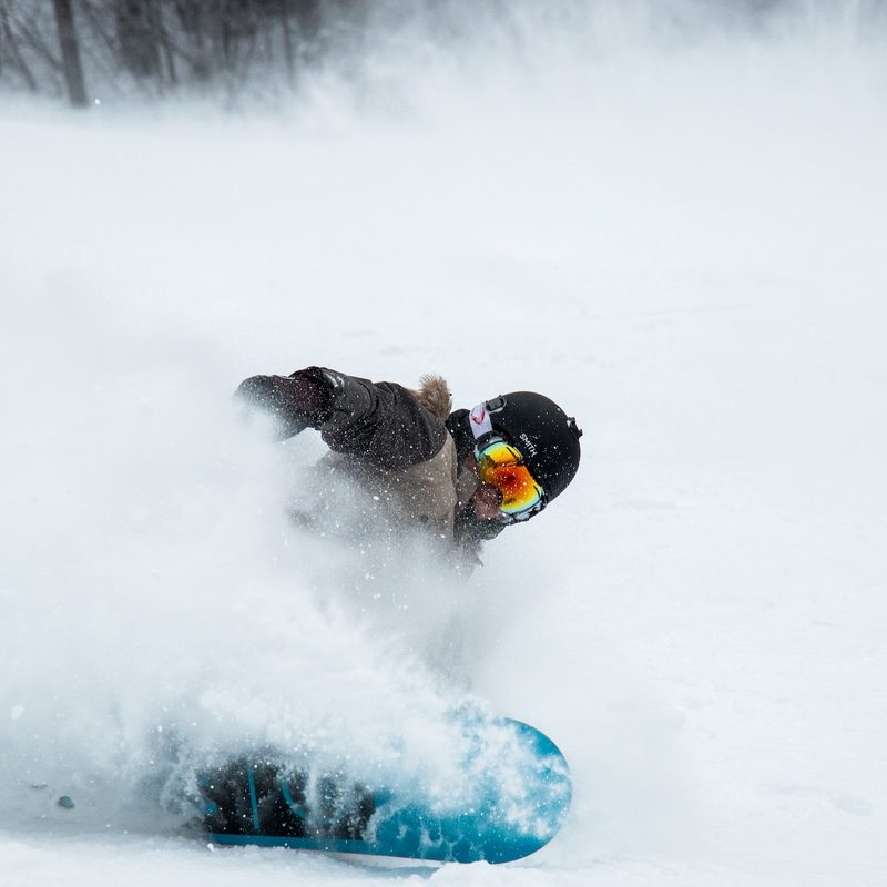 A snowboarder sprays snow into the air.