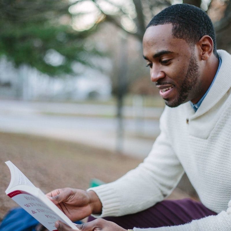 A man reading a book while sitting outside.