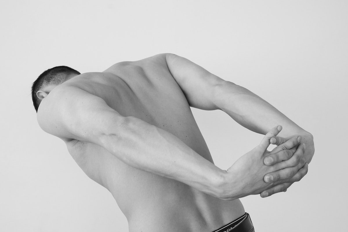 a black and white photo of a man stretching his back and shoulders