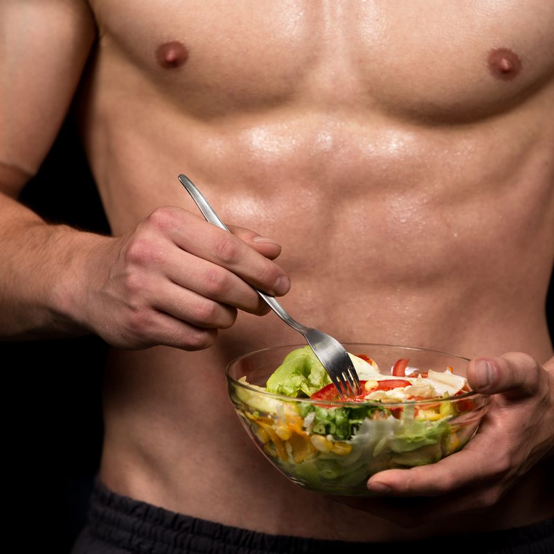Shaped and healthy body building man holding a fresh salad bowl