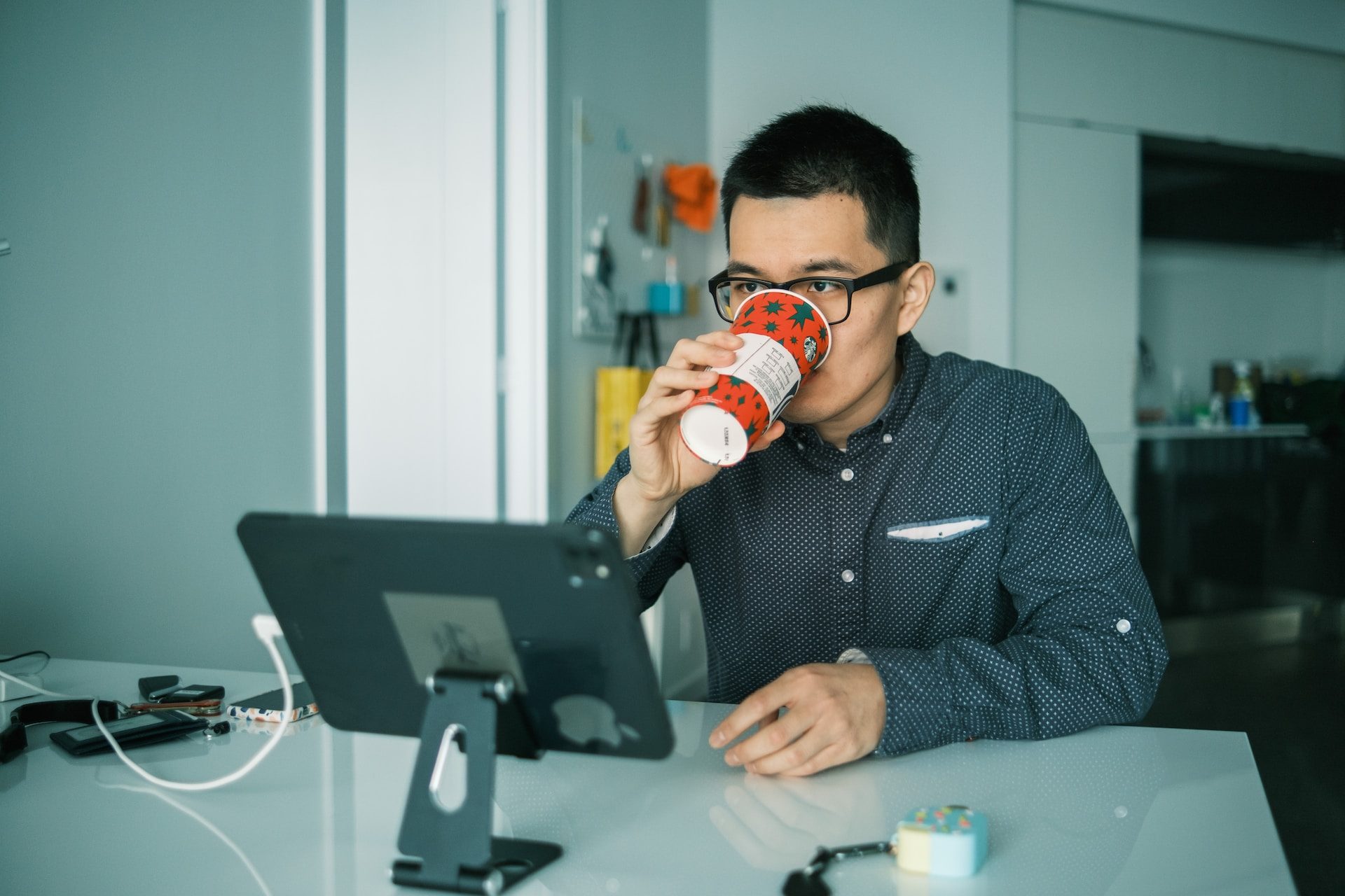 A person sitting at their work desk drinking out of a Starbucks cup.
