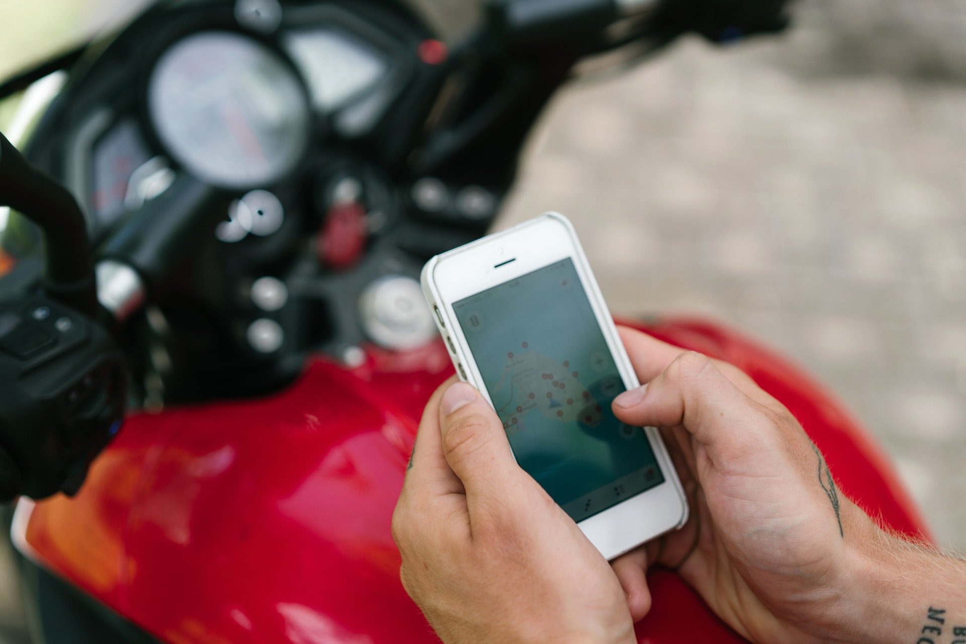 Close-up of phone in man's hands with motorcycle in background