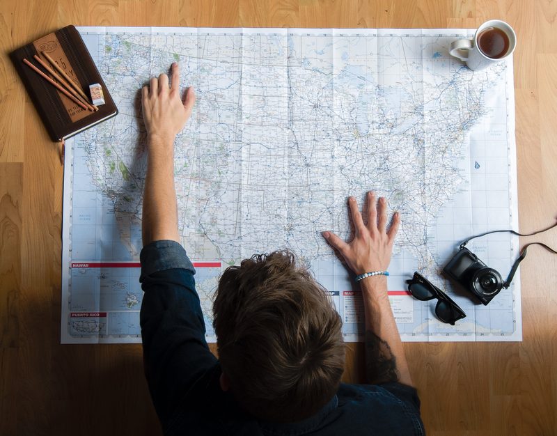 Man pointing to travel destination on paper map