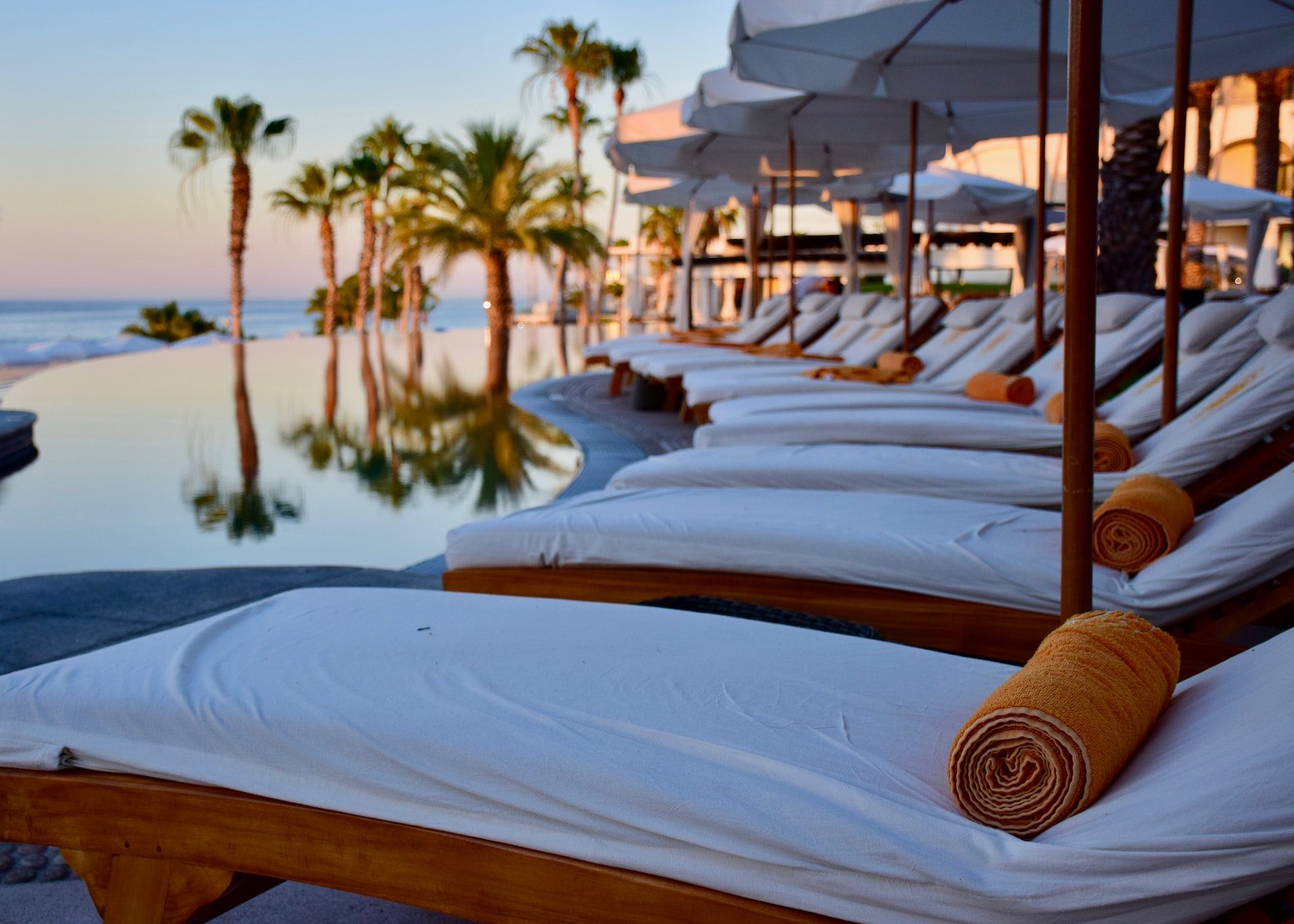 A line of deck chairs for sunbathing lined up poolside at a Caribbean resort at sunset