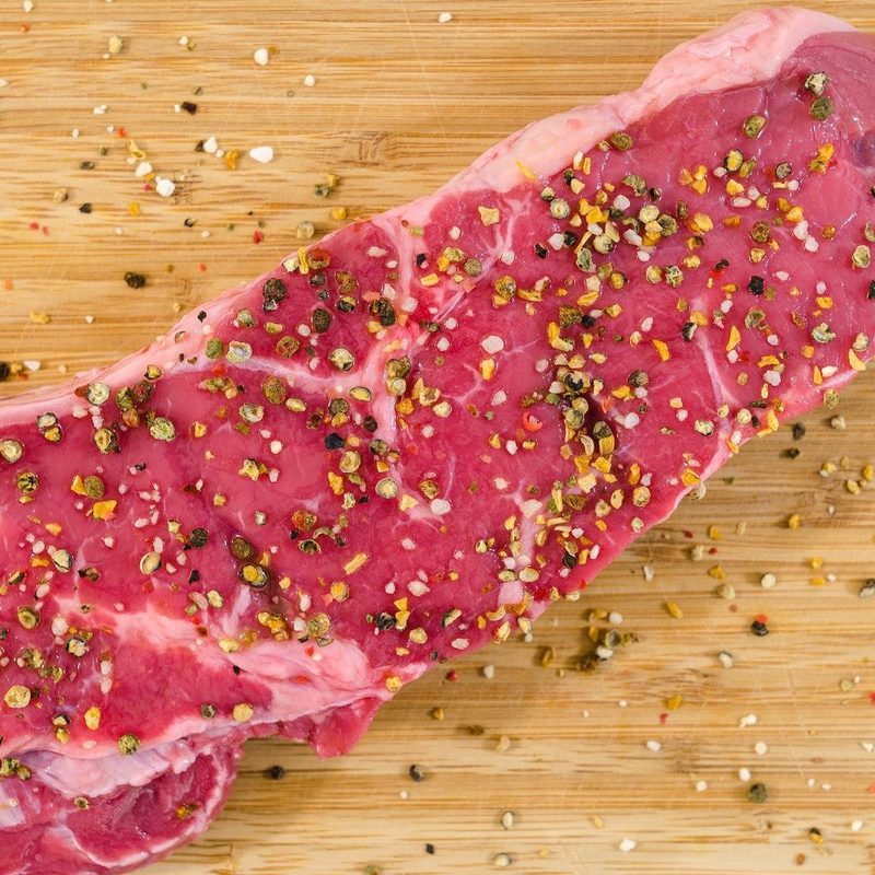 Raw, seasoned steak on cutting board