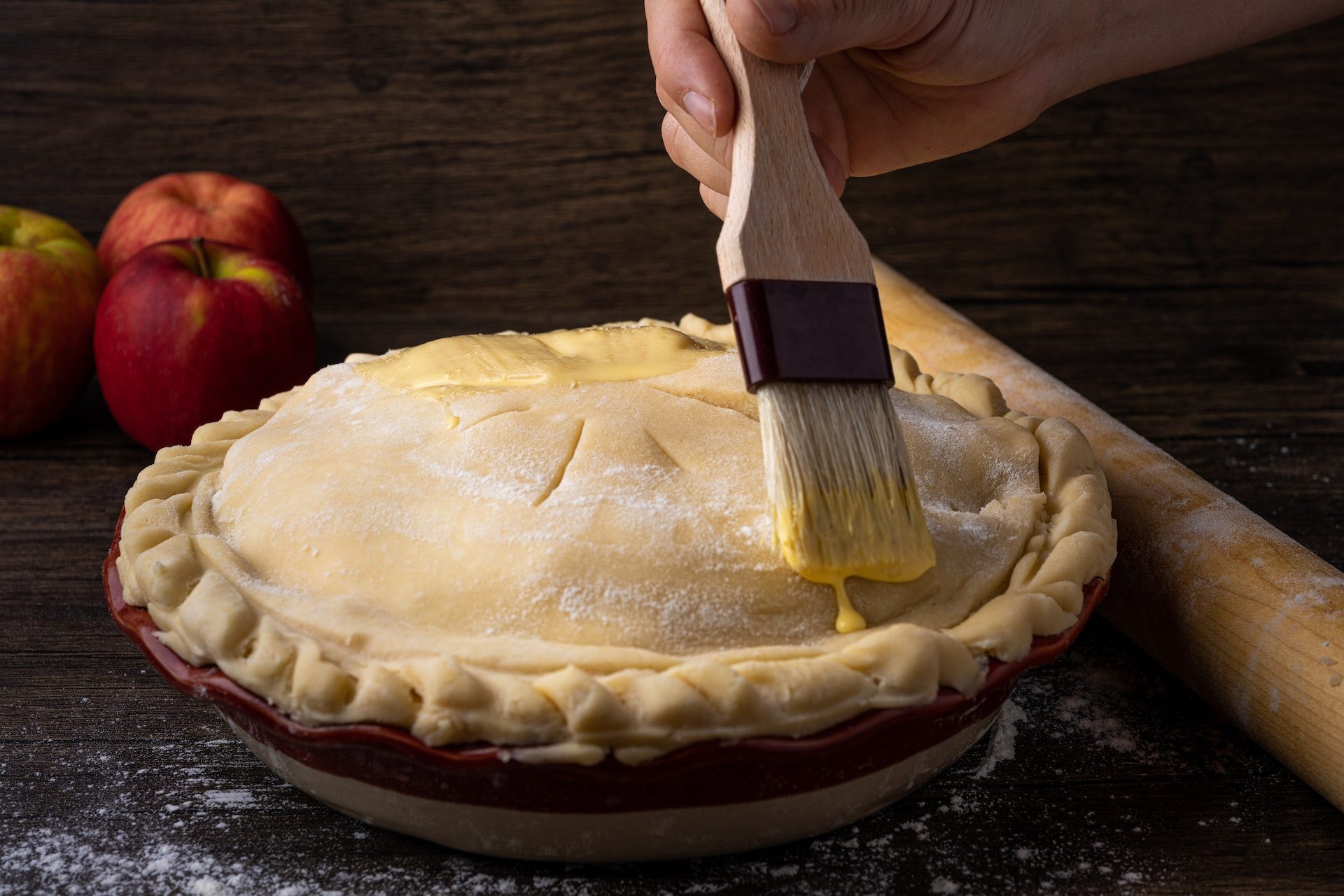 Person brushing pie with egg wash