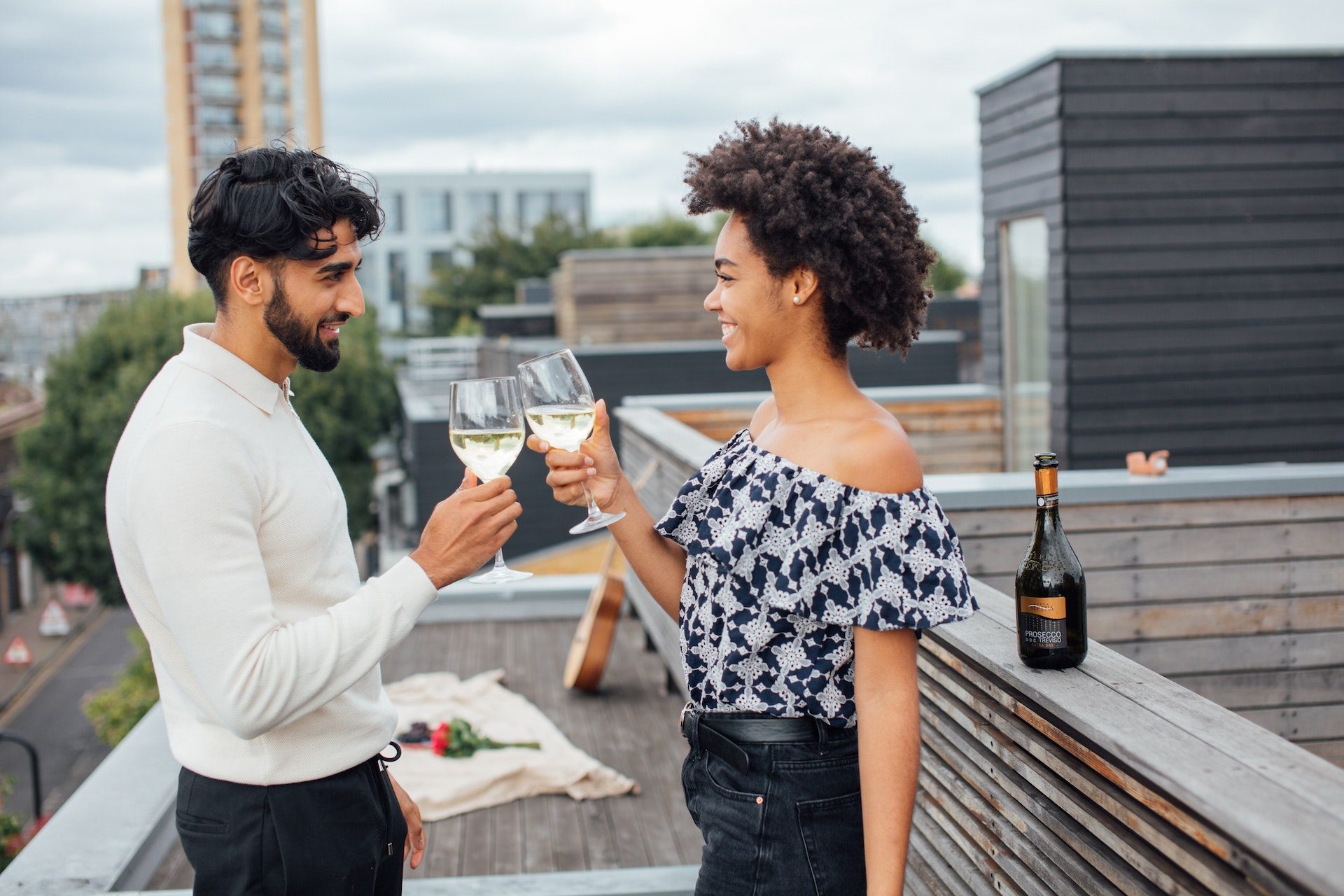 happy couple toasting with white wine on a rooftop