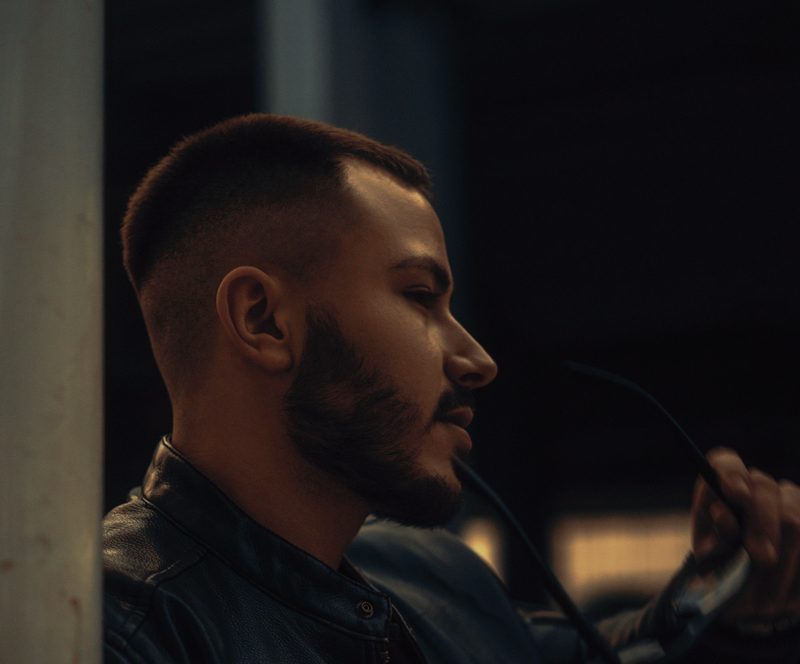 Man with a buzz cut chewing on glasses