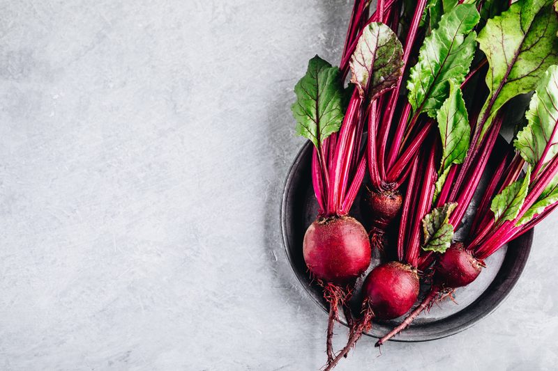 Bunch of fresh raw organic beets with leaves on a gray stone background