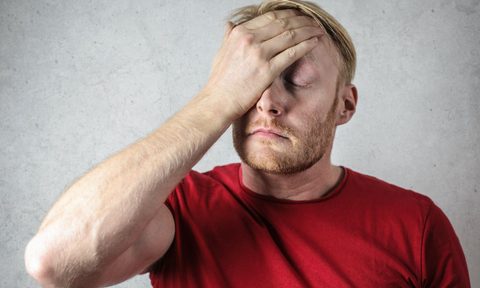 Man in a red shirt with his hand on his head