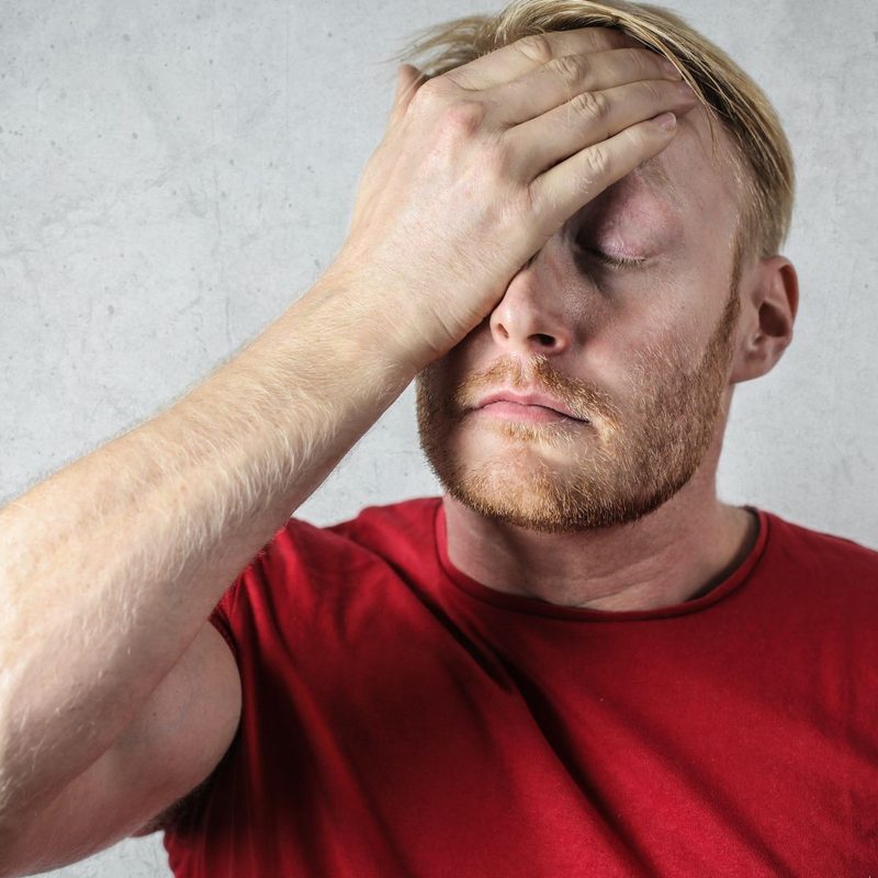 Man in a red shirt with his hand on his head