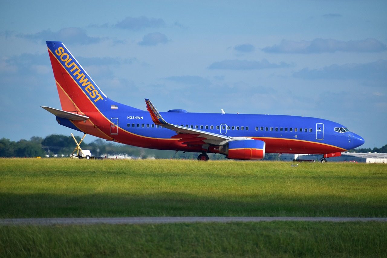 A Southwest Airlines plan stationary on the runway with grass in the foreground