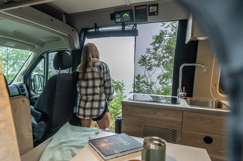 Woman looking out the open sliding door of a Winnebago Solis Pocket 36B campervan.