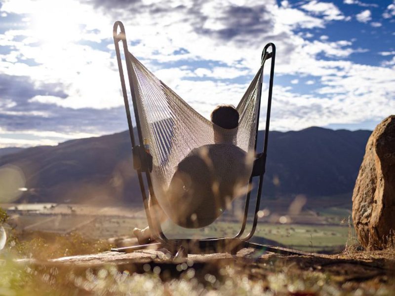 Man swinging in a Yellow Leaf Hammock Chair, overlooking a desert landscape.