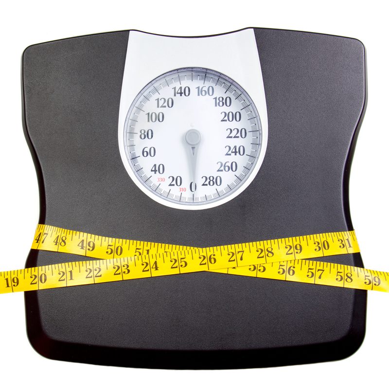 A bathroom scale with a measuring tape, weight loss concept