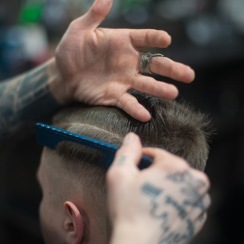 Close up photo of barber combing man's hair