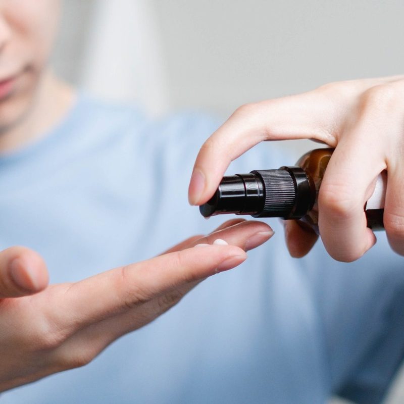 Man dispensing hair serum into hand