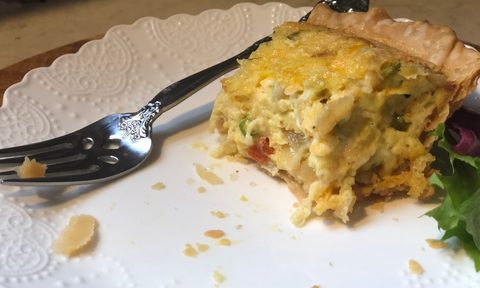 A slice of quiche on a white plate