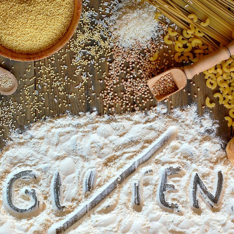 Gluten-free cereals corn, rice, buckwheat, quinoa, millet, pasta and flour with scratched text "gluten"