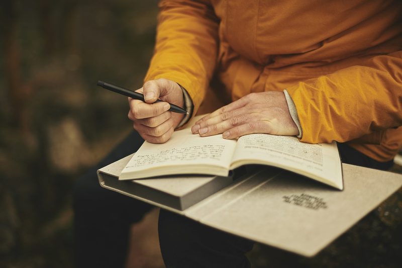 Person sitting with journal opened and pen in hand