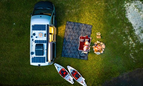 Aerial view of a couple relaxing on an outdoor blanket beside an Airstream Interstate 19X Touring Coach.