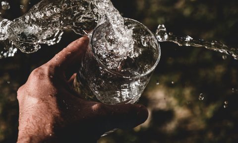 Hand holding glass of water hydration splash