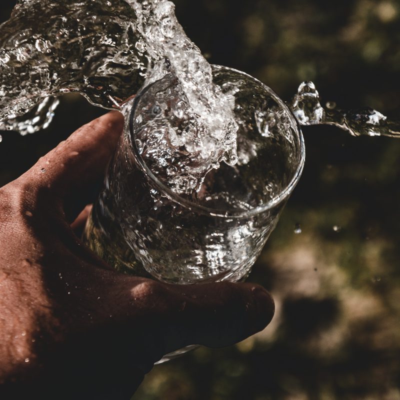 Hand holding glass of water hydration splash