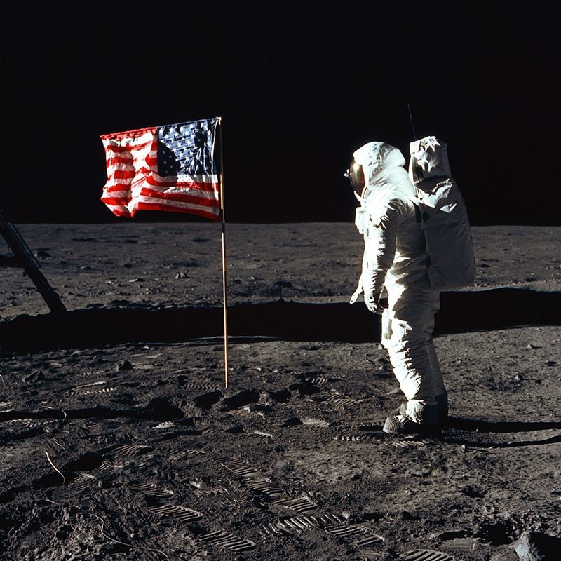 Buzz Aldrin on the moon standing in front of the American flag.