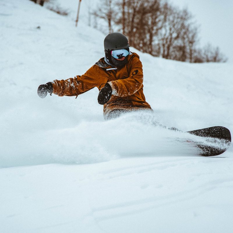 A man on a snowboard rips a turn in soft snow.