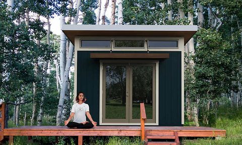 A person doing yoga outside of a she shed.