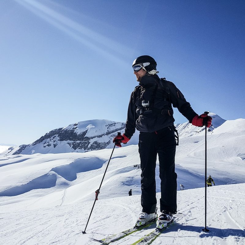 A man standing on the monuntain wearing skis.