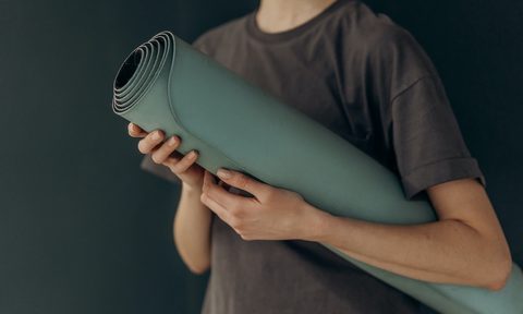 a man holding a green yoga mat
