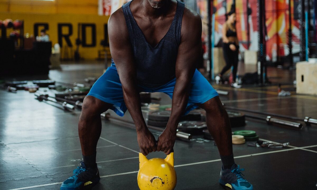 Man with yellow kettlebell squatting