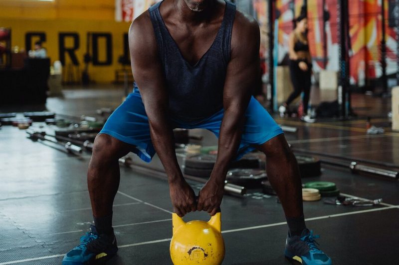 Man with yellow kettlebell squatting