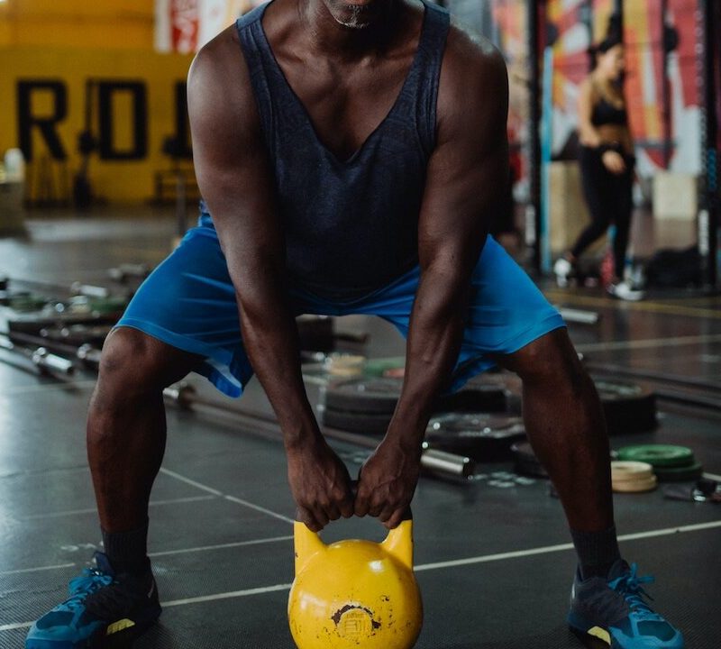Man with yellow kettlebell squatting