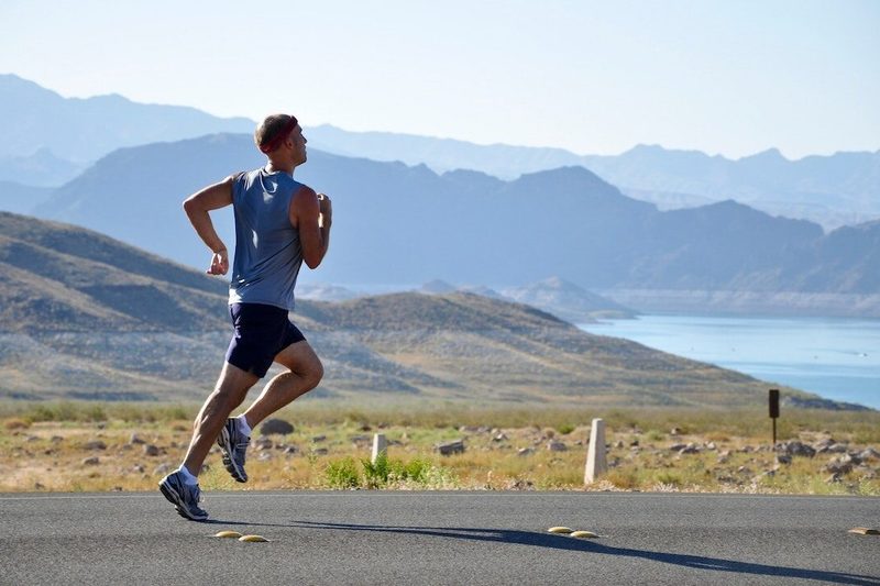 Man running by mountains on a road