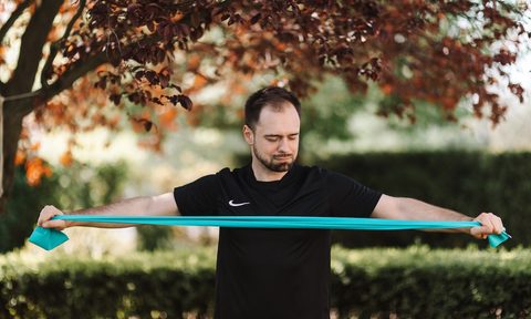 Man using a teal resistance band outside